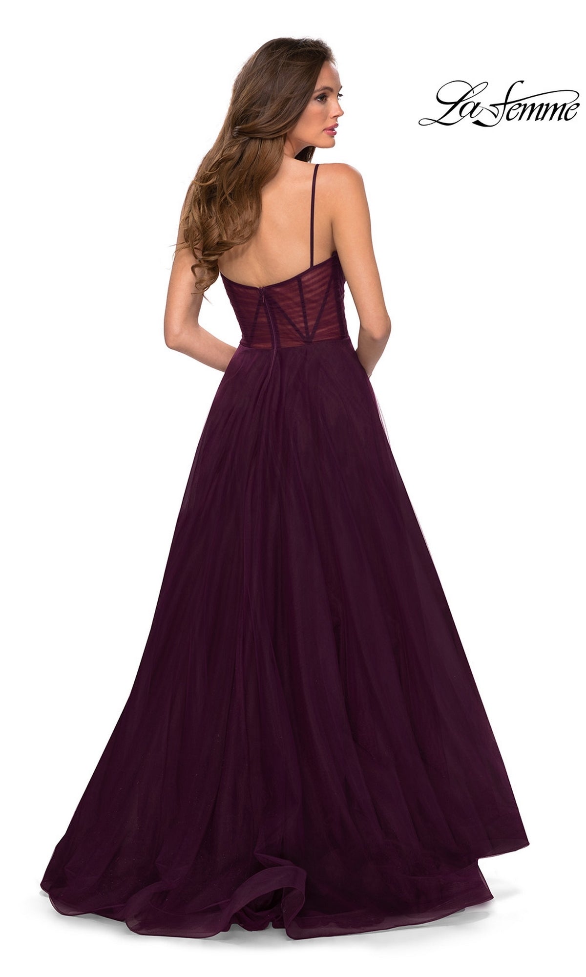 A woman with long brown hair wears the La Femme Sheer-Waist Long A-Line Prom Dress 29076, a floor-length, sleeveless dark purple gown with thin straps and a semi-sheer back. The La Femme logo is visible in the top right corner.